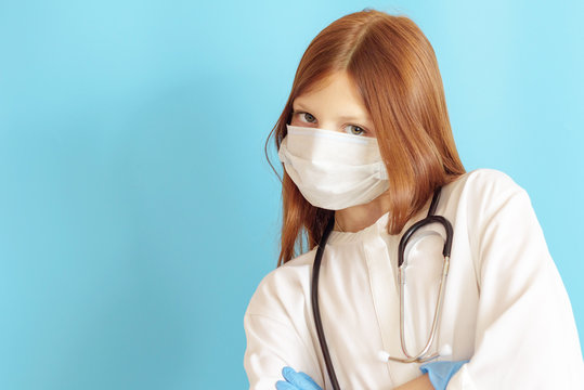 A Teen Girl Plays Doctor, A Concept Of Choosing A Profession For A Child, A Red Hair Girl In A White Shirt, Wearing A Protective Face Mask And With A Phonendoscope In Her Hands