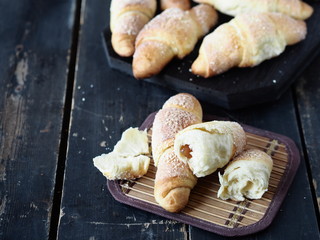 Croissants sprinkled with sesame and sugar on a dark wooden background.Homemade cake.