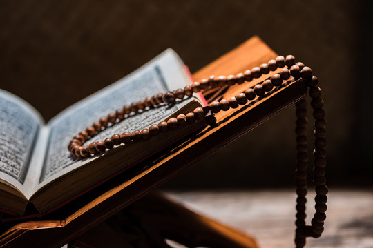 Islamic prayer beads or tasbih on rihal or quran book stand made from carved wood. It is suitable for background of Ramadan-themed design concepts or other Islamic religious events.