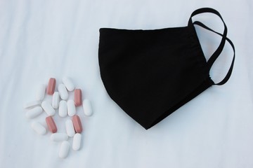Black medical face shield with place for text on a white background with pills. Black face shield...