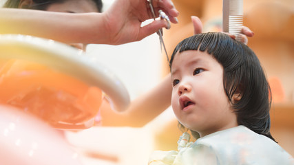 Home haircut of 2 year old Asian toddler by mother in the household during Covid-19 coronavirus pandemic, self-quarantine, social distancing, DIY, mother daughter relationship, homeschool, family bond