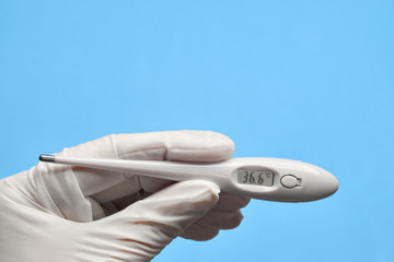 Medical thermometer in hands on a blue background.
