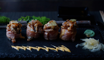 seared salmon and eel sushi rolls on dark background