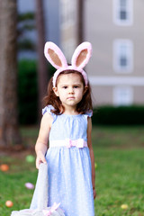 Little toddler girl with bunny ears. Easter egg hunt. - 337055864