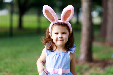 Little toddler girl with bunny ears. Easter egg hunt. - 337055887