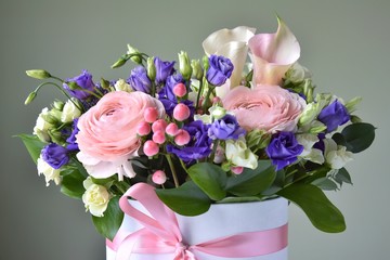 Amazing tender bouquet with pink ranunculus, violet Alstroemeria flowers and tiny white roses in cardboard box with pink ribbon. Beautiful bunch of spring flowers. Easter gift. Seasonal spring flowers