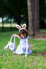 Little toddler girl with bunny ears. Easter egg hunt. - 337056038