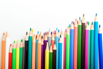 Group of many mixed colourful pencils isolated isolated on a white paper, children school or office suppliers photographed with soft focus from side view, with space for text
