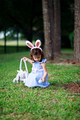 Little toddler girl with bunny ears. Easter egg hunt. - 337056074