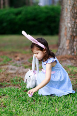 Little toddler girl with bunny ears. Easter egg hunt. - 337056217
