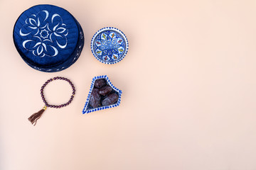 Muslim islamic faith concept taqiyah skullcap , red rosary, dates in the bowl in the Arabic style. Neutral beige background. layout and Space for text.