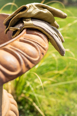 Gartenhandschuhe liegen nach getaner Arbeit auf dem Rand einer Amphore im Garten - Hochformat