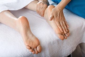 A woman came to a professional for foot massage. Close-up of female legs. Professional masseur doing foot massage
