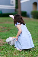 Little toddler girl with bunny ears. Easter egg hunt. - 337057463