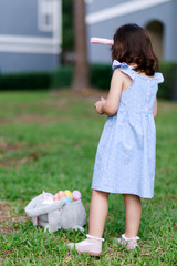 Little toddler girl with bunny ears. Easter egg hunt. - 337057488