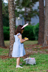 Little toddler girl with bunny ears. Easter egg hunt. - 337057603