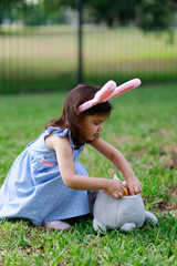 Little toddler girl with bunny ears. Easter egg hunt. - 337057663