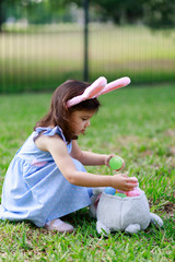 Little toddler girl with bunny ears. Easter egg hunt. - 337057691