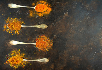 A variety of spices in spoons on a dark table. Cooking background. View from above. Ingredients for cooking. Table background menu. Copy space.