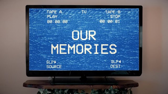 A modern flat TV screen playing an old damaged VHS tape (bad signal coming from a double deck), with the text Our memories.
