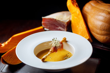 pumpkin soup with pumpkin in white bowl on a black background 