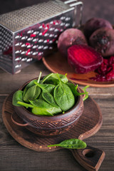 Fresh baby spinach and boiled beetroot on wooden cutting board. Healthy food concept. 