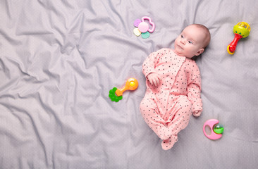 Cute baby playing with colorful rattle toy. New born child, little girl looking at the camera and...