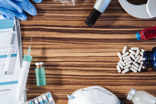 Medical still life. Wooden doctor desk background, horizontal medical concept copy space. Flat lay composition with siringe, needle, medical bottle, mask, pills, plastic glasses and medical form. 