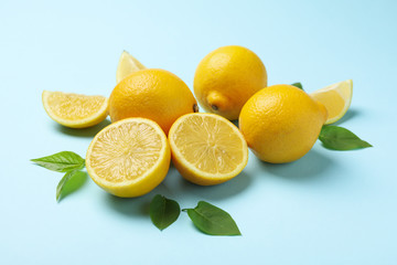 Fresh lemons with leaves on blue background, close up. Ripe fruit