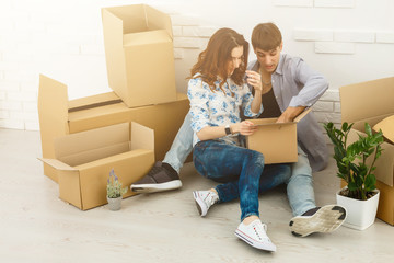 Fototapeta na wymiar Smiling couple leaning on boxes in new home