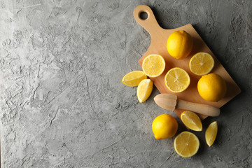 Obraz na płótnie Canvas Board, lemons and juicer on gray background. Ripe fruit