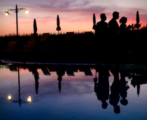Gruppo di ragazzi in silhouette riflessi nell'acqua della piscina