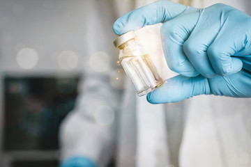 Doctor holding vaccine for prevention, immunity and treatment from covid-19 infection or coronavirus. Concepts of disease prevention. Focus on vaccine bottle , blurred background.