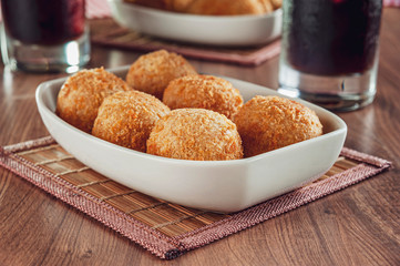 Brazilian appetizer deep fried cheese croquette with two glasses of drink - Bolinha de queiijo