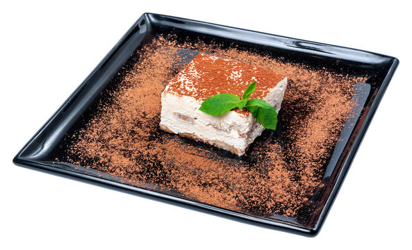 tiramisu cake on a black plate. tasty italian dessert decorated with mint
