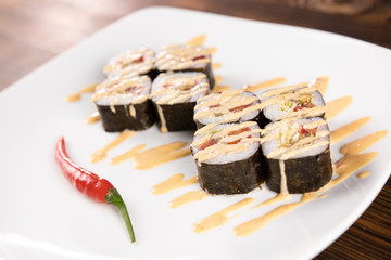 sushi rolls with red pepper chilli on white plate close up