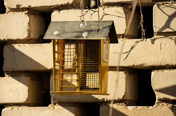 Yellow bird feeder at the brick wall