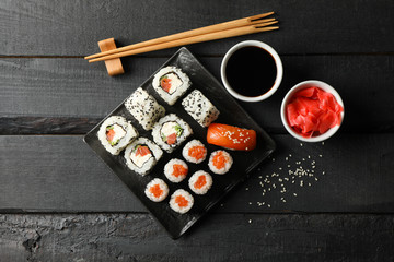 Tray with delicious sushi rolls on wooden background, top view. Japanese food