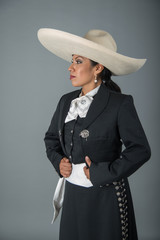 Mujer charra, latina morena con sombrero y traje tipico de charro mexicano, moño blanco, folklor...