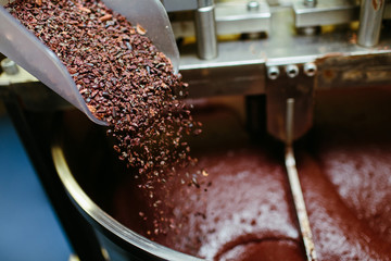 Artisan chocolate making, adding cocoa grits. © primipil