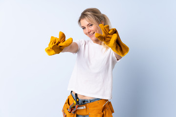 Electrician woman over isolated blue background smiling and showing victory sign