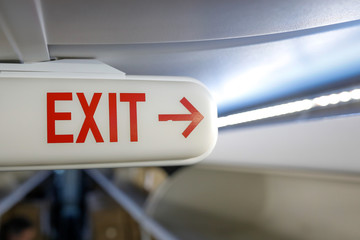Shallow depth of field image (selective focus) with the exit sign on the ceiling of a commercial airplane.