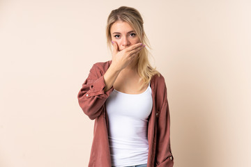 Blonde woman over isolated background covering mouth with hand