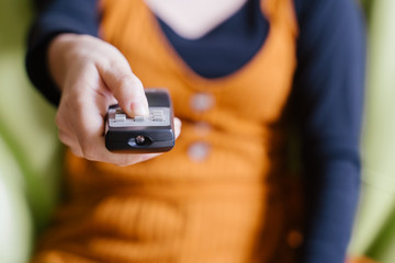 Unrecognizable woman changing the television chanel sit on the couch picking a show to watch online. Movies and cinema series on streaming content online. People having leisure at home in quarantine.