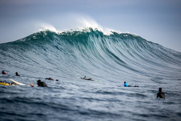 surfers paddling in massive waves