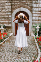 Fototapeta na wymiar girl in a white dress and a straw hat walks in a beautiful park. bride in a vintage wedding dress in the garden.