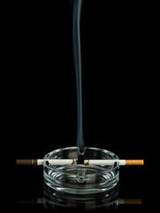 Laminar stream of smoke from two cigarettes in glass ashtray. Tet-a-tet.