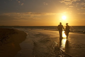 Couple walking on the beach at sunset 