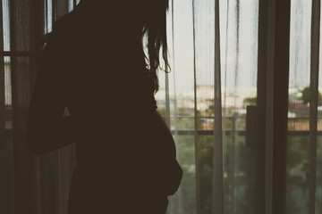Slihouette of pregnant woman in the bedroom