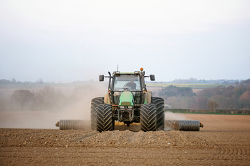 Fototapeta premium Green tractor rolling preparing the fields in spring in England to feed the nation during lockdown